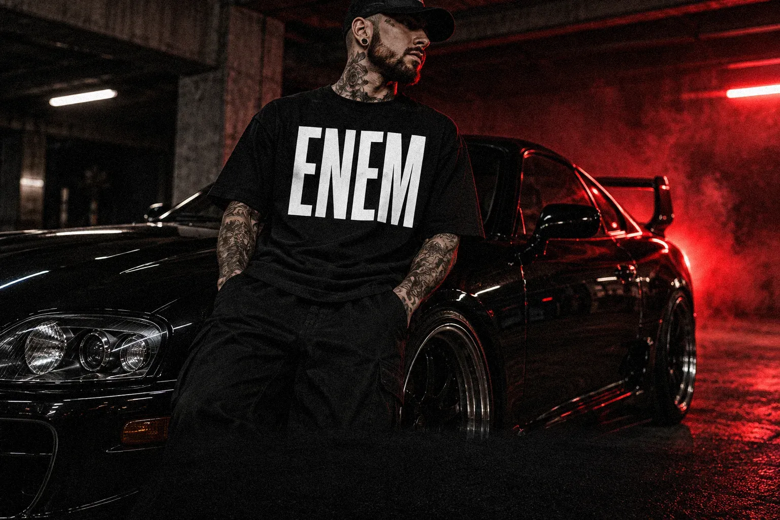 ENEM Car Culture: رجل بقميص ENEM بجانب سيارة رياضية سوداء تحت ضوء أحمر