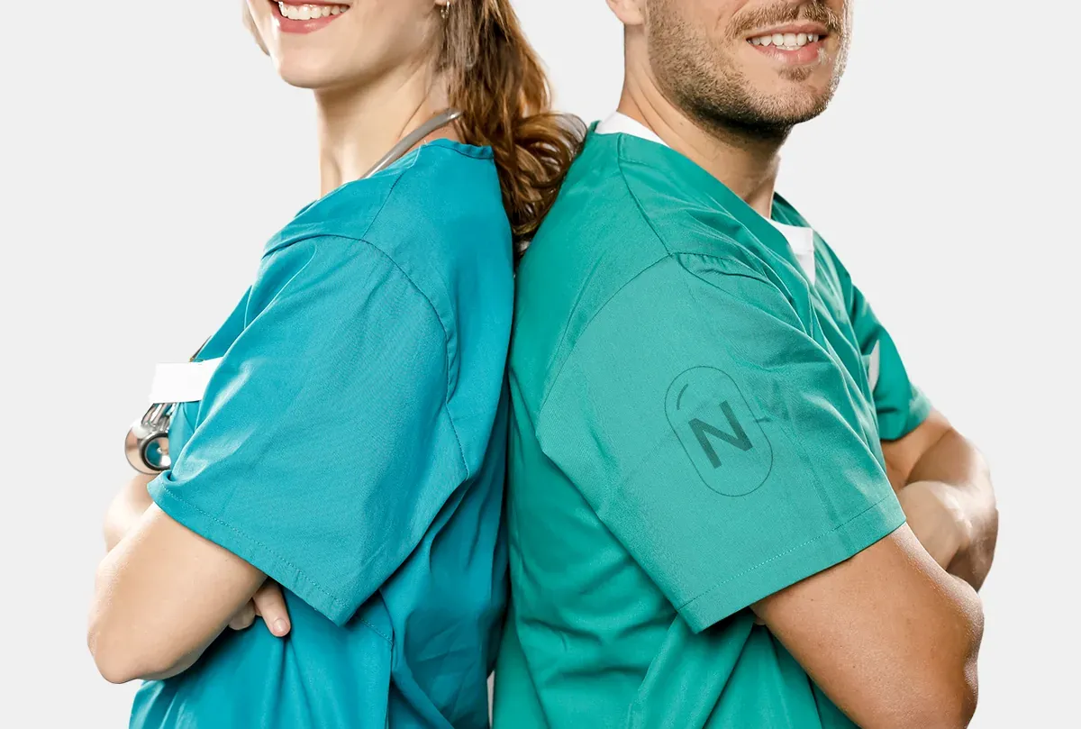 Two clinicians in teal scrubs, the NeuroSoins N monogram on a sleeve